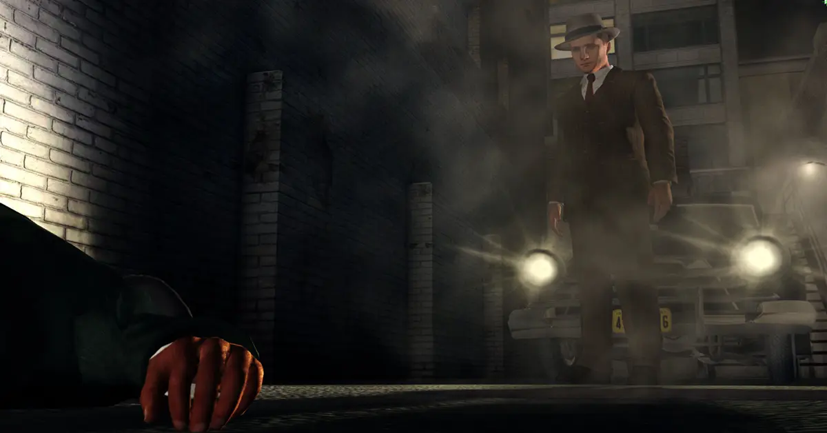 El detective de L.A. Noire, Cole Phelps, de pie en una calle de la década de 1940 tenuemente iluminada
